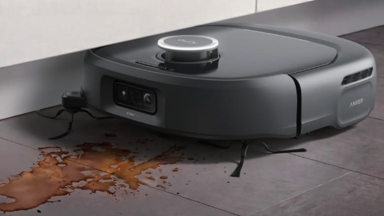 Robô aspirador eufy passando sobre uma poça de líquido derramado no piso da cozinha