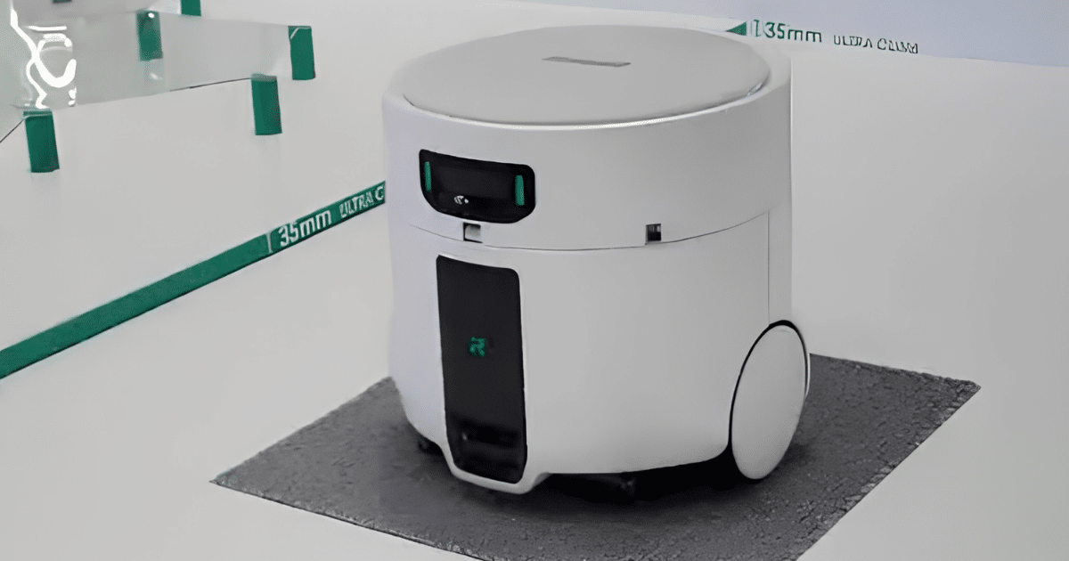 Unidade principal do Roomba Duo, em formato de tambor branco com rodas grandes, sobre um tapete no estande da iRobot