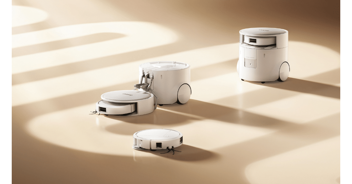 Renderização do Roomba Duo com o braço mecânico soltando o robô companheiro no chão ao lado de um Roomba comum, com a base AutoWash ao fundo