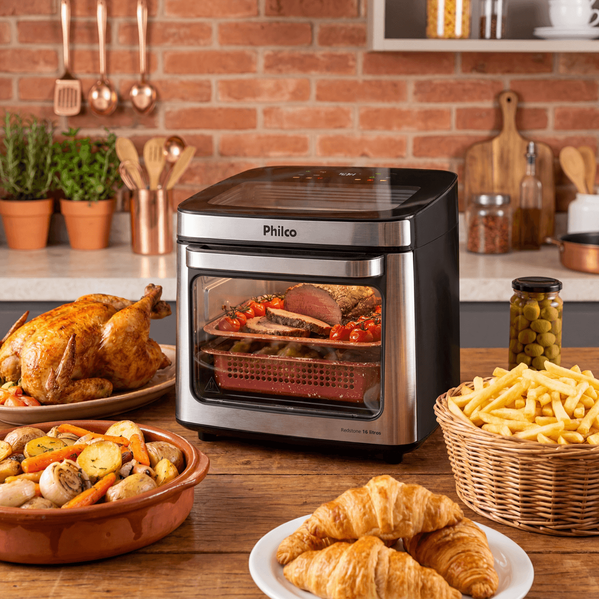 Air fryer Philco PAF16B de 16 litros na bancada, com carne e legumes nas duas assadeiras