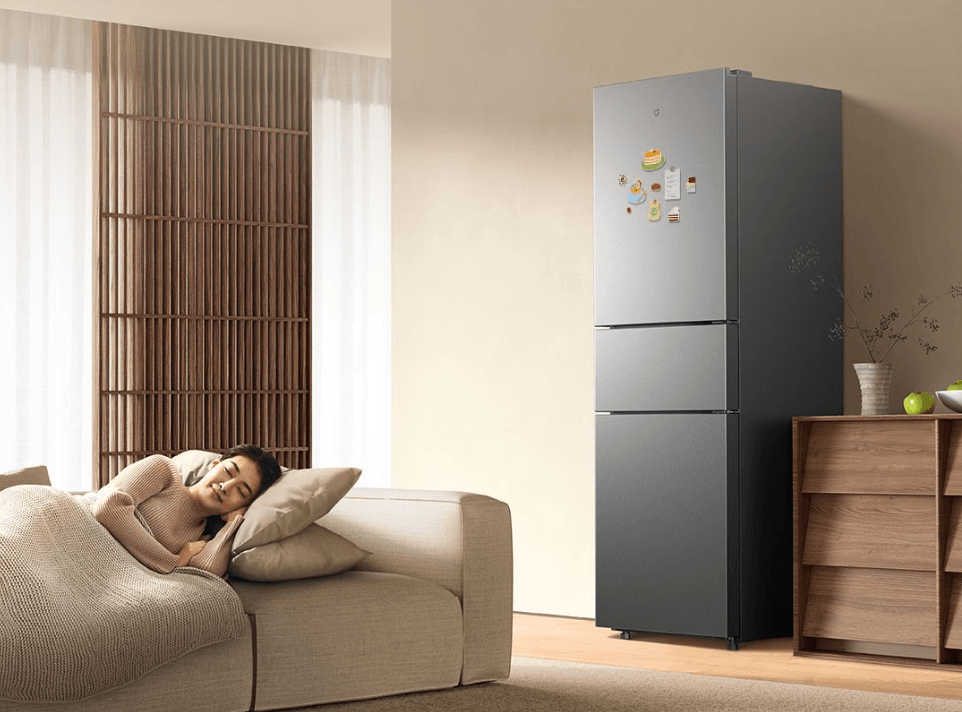 Geladeira Mijia 271L de três portas em uma sala integrada, ao lado de um sofá